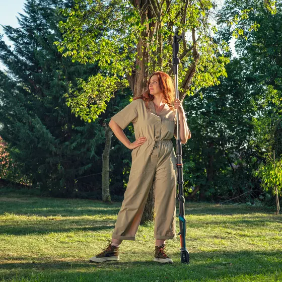 A woman holding a GARDENA Battery telescopic pruning lopper
